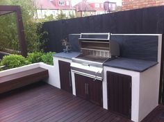 an outdoor bbq grill on a deck in the middle of a backyard with wooden floors