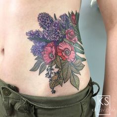 a close up of a woman's stomach with flowers and leaves on the side