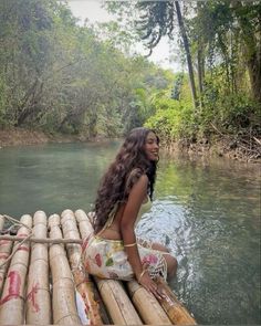 a woman sitting on top of bamboo raft in the middle of a body of water