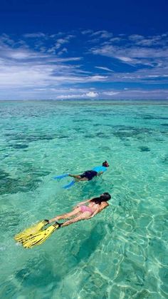 two people are swimming in the clear blue water