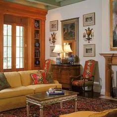 a living room with couches, chairs and paintings on the wall in front of a fireplace