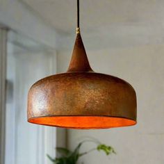 a hanging light that is made from an old metal drum and has a copper pattered finish