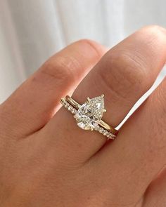 a woman's hand with a yellow gold ring and two diamond engagement rings on it