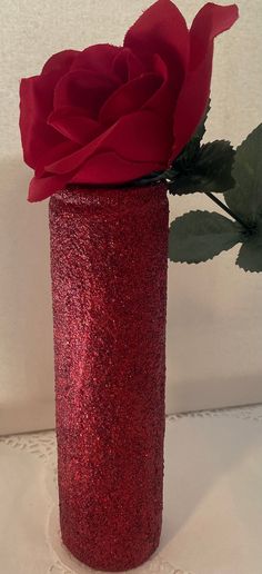 a red vase with a rose in it