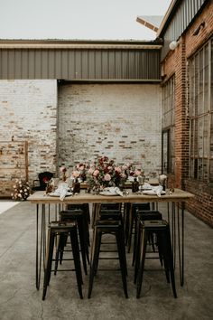 an outdoor table set up with flowers and place settings for the guests to sit at