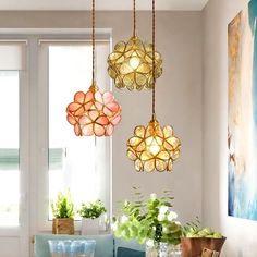 three lights hanging from the ceiling above a table with flowers in vases on it