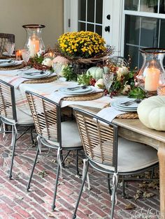 a table set with candles, plates and pumpkins on it for thanksgiving dinner outside