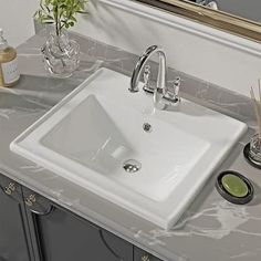 a bathroom sink sitting on top of a counter next to a mirror and soap dispenser