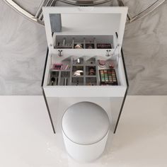 a white toilet sitting inside of a bathroom next to a wall mounted vanity with drawers