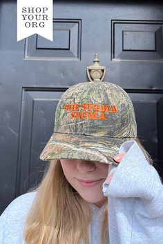 a woman wearing a hat with the words phi sigmma on it in front of a door