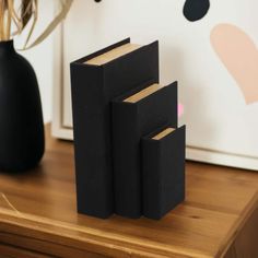 three black bookends sitting on top of a wooden table next to a vase