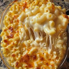 a spoon full of macaroni and cheese being lifted from the casserole dish