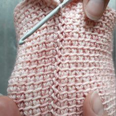 someone is crocheting the stitches on a pink knitted sweater