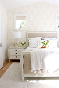 a white bed sitting in a bedroom next to a window