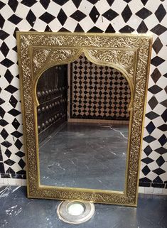 a mirror sitting on top of a tiled floor next to a black and white wall