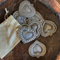 several silver heart shaped ornaments sitting on top of a wooden table next to a bag