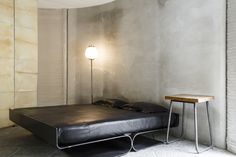 a bed sitting in the middle of a room next to a table with a lamp on it