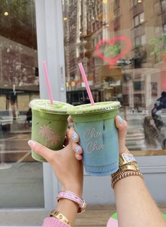 two people holding up drinks in front of a store window with the words chacha cha on it