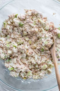 a glass bowl filled with tuna salad and a wooden spoon on top of the bowl