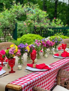 a table set with red and white checkered cloths, vases filled with colorful flowers