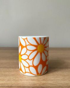 an orange and white coffee cup sitting on top of a wooden table