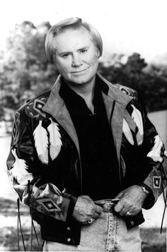 an old black and white photo of a man wearing a jacket with feathers on it