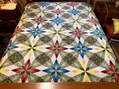 a bed with a quilt on top of it in a room next to a dresser