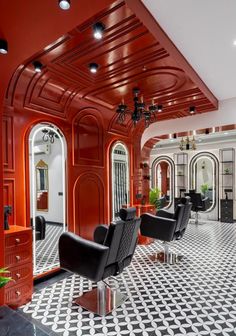 the interior of a salon with black and white tile flooring, chandeliers and chairs