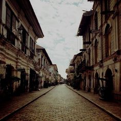 an empty cobblestone street with old buildings on both sides and sky in the background