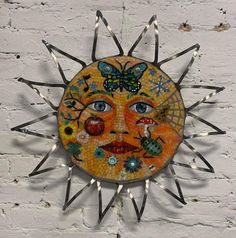 a sun face with many different designs on it's face and two butterflies flying around