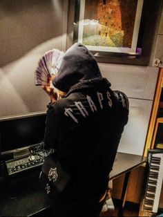 a person wearing a hoodie and holding a fan in front of a piano keyboard