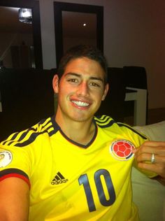 a man sitting on top of a couch wearing a yellow shirt and smiling at the camera