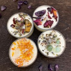 four bowls filled with different types of food on top of a wooden table next to dried flowers