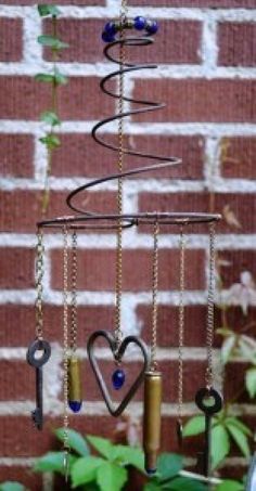 a wind chime hanging from a brick wall next to some plants and other items