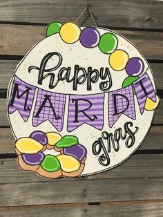 a sign that says happy mardi gras hanging on a wooden fence with purple and yellow decorations