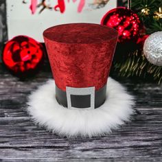 a red top hat sitting on top of a wooden table next to christmas decorations and ornaments