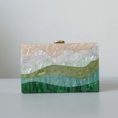 Looking for a unique and stylish piece with a designer touch? You'll love this beautiful Luxury Emerald Striped Acrylic Clutch Bag! With its beautiful pearlescent sheen, this stylish clutch won't go unnoticed. Perfect to dress up an outfit for a party or a wedding. Available with single chain or two chains including a gorgeous green handle, pick your favourite! Style: Eclectic Boho Chic Occasions: Evening, garden party or use as wedding bag Smart features: Hasp closure, cell phone fit, mini hand Acrylic Box Clutch, Bridal Bags, Wanderlust Fashion, Cute Mini Bags, Acrylic Bag, Green Clutches, Clutch Bag Wedding, Acrylic Clutch, Shell Bag