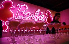 several martini glasses lined up in front of a neon sign with the word barbie's on it