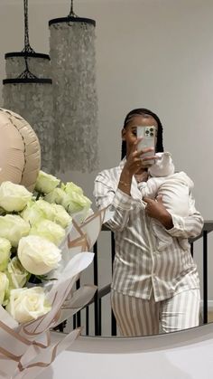 a woman taking a selfie while holding a camera next to a bouquet of roses