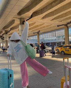 a girl in pink pants and white hoodie pulling luggage