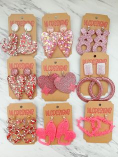 six pairs of pink and red glittered heart shaped hair clips with bows on them