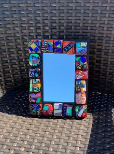 a mirror sitting on top of a table next to a wicker chair with a blue sky in the background