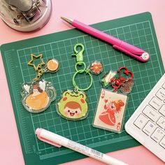 various keychains and magnets sitting on top of a green cutting board next to a keyboard