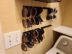 there are many pairs of sunglasses hanging on the wall above the washer and dryer