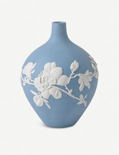 a blue vase with white flowers painted on the front and sides, sitting against a white background