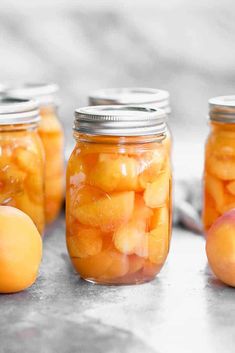 four jars filled with peaches sitting on top of a table