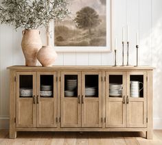 a wooden cabinet with plates and vases on top