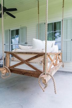 a porch swing with pillows on it and a ceiling fan in the back ground area