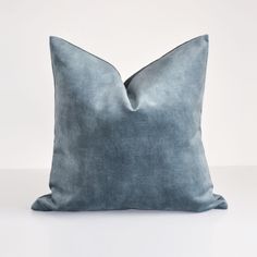 a blue velvet pillow on a white surface