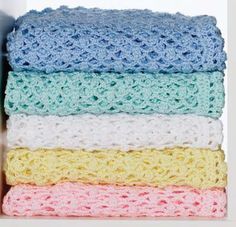 a stack of crocheted blankets sitting on top of a white shelf next to a bottle